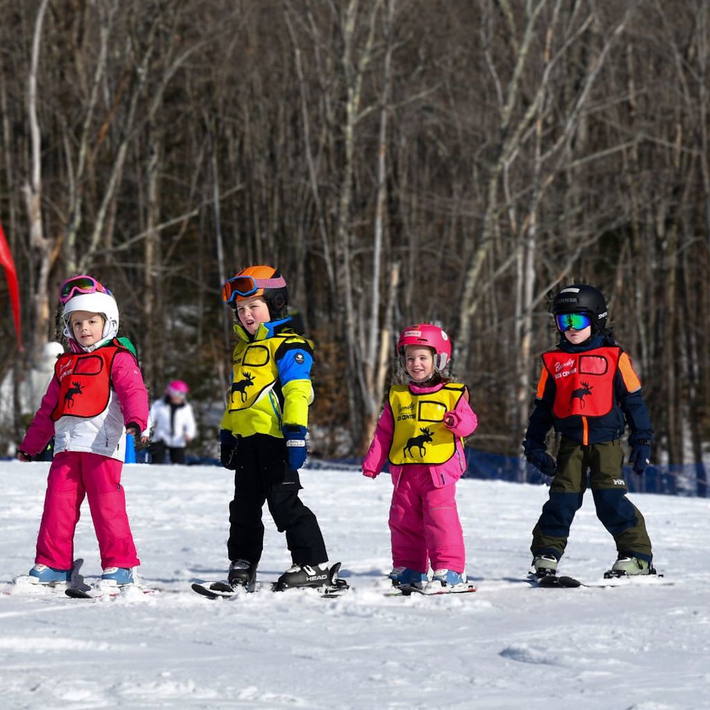 instructor teaching child how to snowboard